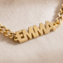 Close-up of block capital letters cut from flat gold and linked into a curb chain