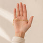 Gold name bracelet lying flat across an open palm to show its real size
