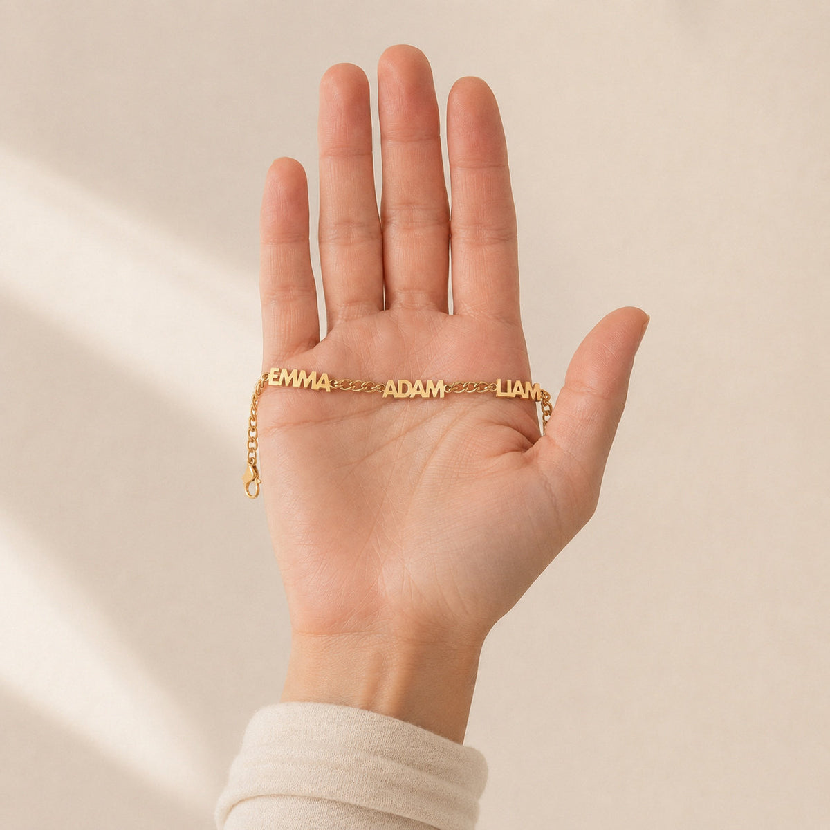 Gold name bracelet lying flat across an open palm to show its real size